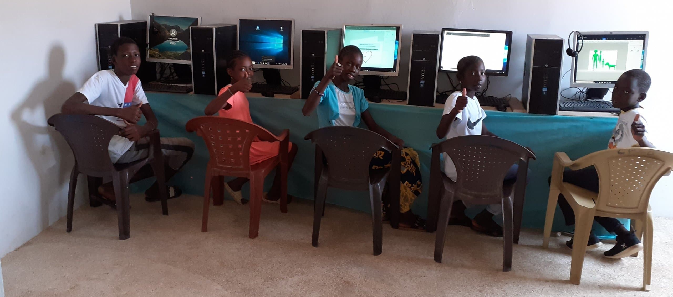 Children smiling at computers in the new lab