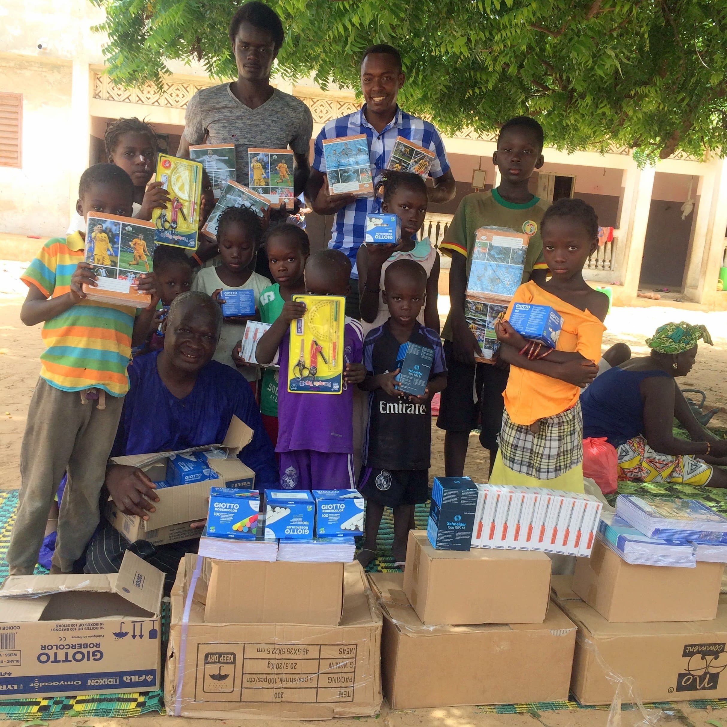 Children and adults posing with boxes of school supplies, notebooks and stationery